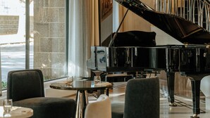 A grand piano in a spacious, elegantly furnished room with large windows and a staircase. - The Royce (Melbourne)