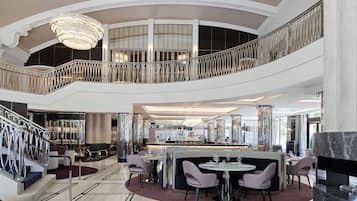 Stunning multi-level interior with grand staircase, dining area, bar, and balcony with ornate railings.