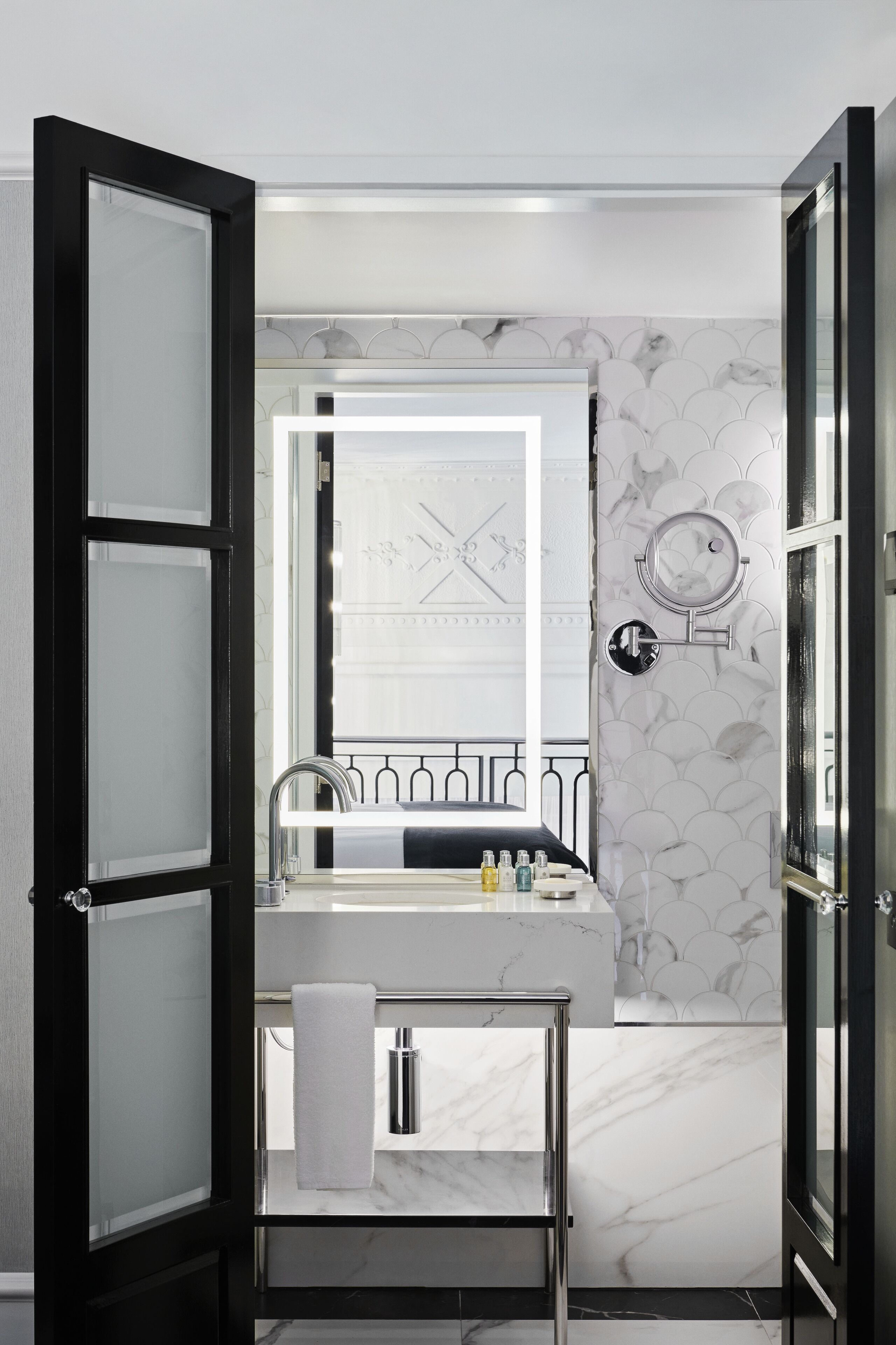 A modern bathroom with a marble sink, a mirror, and a towel rack.