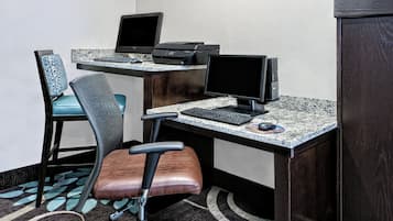 Un espacio de trabajo con dos escritorios, cada uno con monitor de computadora, teclado y ratón. Hay dos sillas de oficina de diseños distintos.