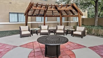 A covered outdoor seating area with wicker furniture and a central table.