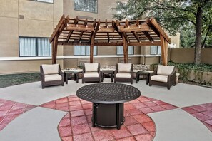 A covered outdoor seating area with wicker furniture and a central table. - Staybridge Suites Lubbock - University Area by IHG (Lubbock)