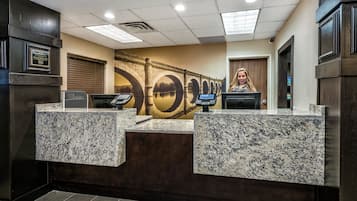 A reception desk with a stone counter, a large wall mural, and a door to the right.