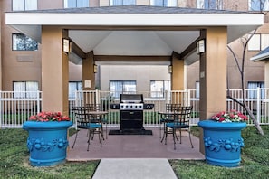 An outdoor patio area with a grill, two chairs, and two large flower pots. - Staybridge Suites Lubbock - University Area by IHG (Lubbock)