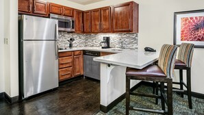 A modern kitchen with wooden cabinets, stainless steel appliances, and a tiled backsplash. - Staybridge Suites Lubbock - University Area by IHG (Lubbock)