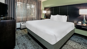 Une chambre d’hôtel avec un grand lit, un téléviseur à écran plat, un bureau et une lampe.