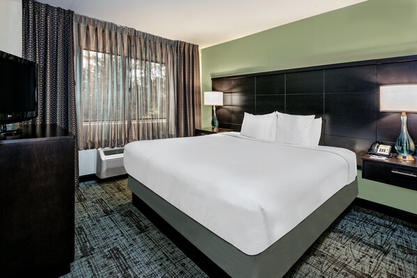 Une chambre d’hôtel avec un grand lit, un téléviseur à écran plat, un bureau et une lampe.