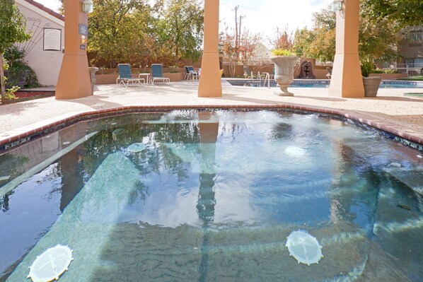 A clear swimming pool with a tiled edge, surrounded by lounge chairs and a pergola structure. - Staybridge Suites Lubbock - University Area by IHG (Lubbock)