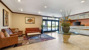 Un hall con mostrador de recepción, dos sofás, una mesa de centro y una planta decorativa.