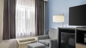 Una habitación de hotel con cama, silla, televisor y calefacción.