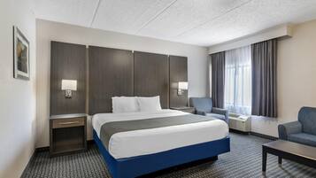 A hotel room with a bed, bedside tables, a desk, a chair, and a large window with curtains.