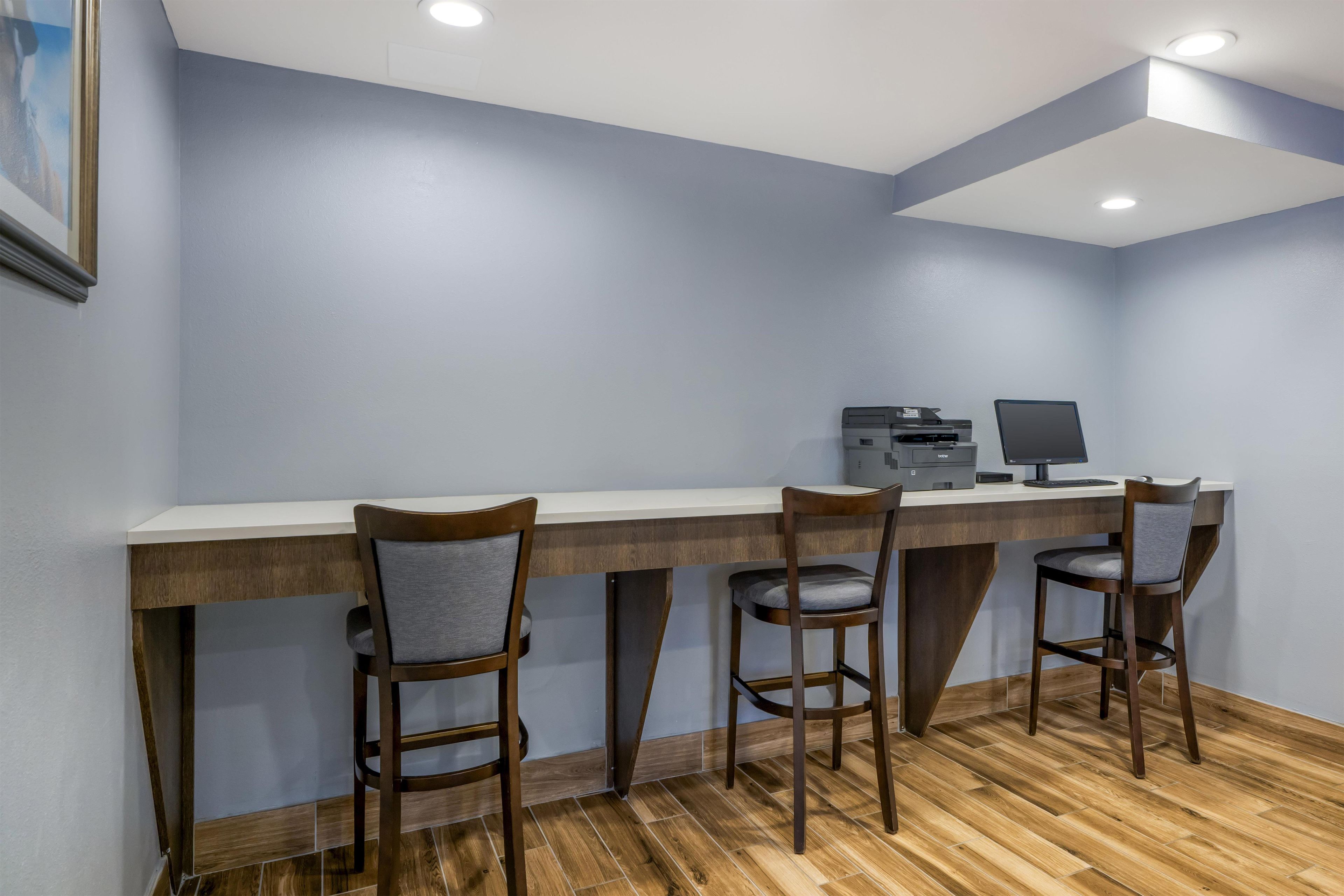 A modern office space with a long desk, three chairs, a computer, and a printer.