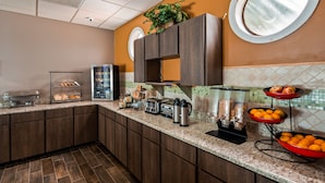 Eine moderne Küche mit Buffet-Einstreuung, darunter ein Kühlschrank, ein Toaster und Kaffeemaschinen.