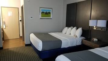 A hotel room with a bed, bedside table, lamp, and a picture on the wall.