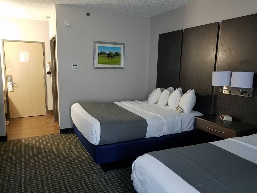 A hotel room with a bed, bedside table, lamp, and a picture on the wall.