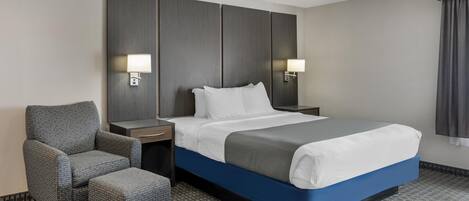 Ein Hotelzimmer mit einem Bett, einem Sessel, einem Nachttisch und einer Wandleuchte.