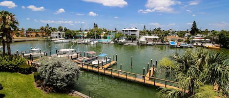 Un puerto deportivo con barcos amarrados, una zona verde y un edificio grande al fondo.