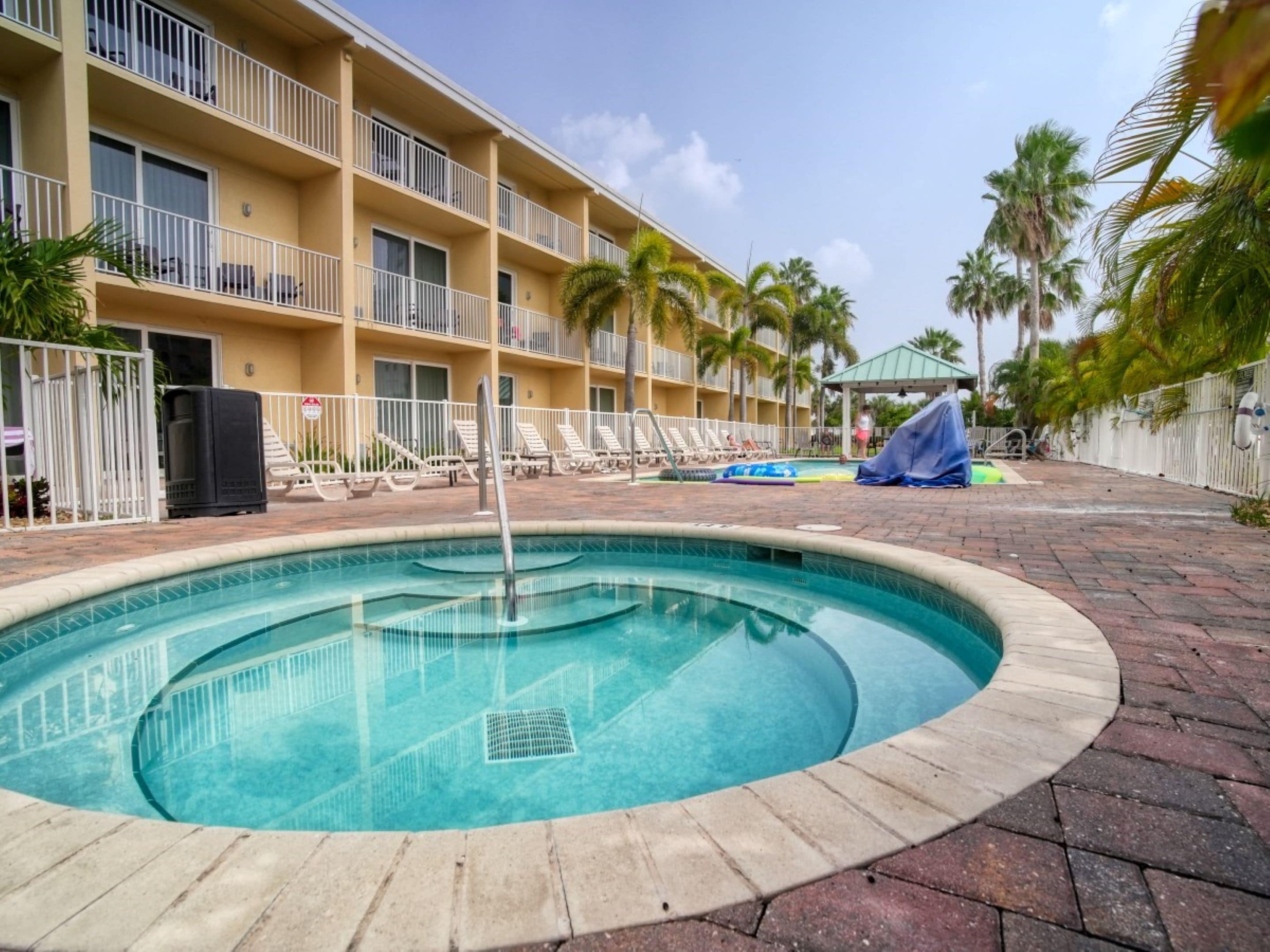 A swimming pool with lounge chairs and a building with balconies in the background.