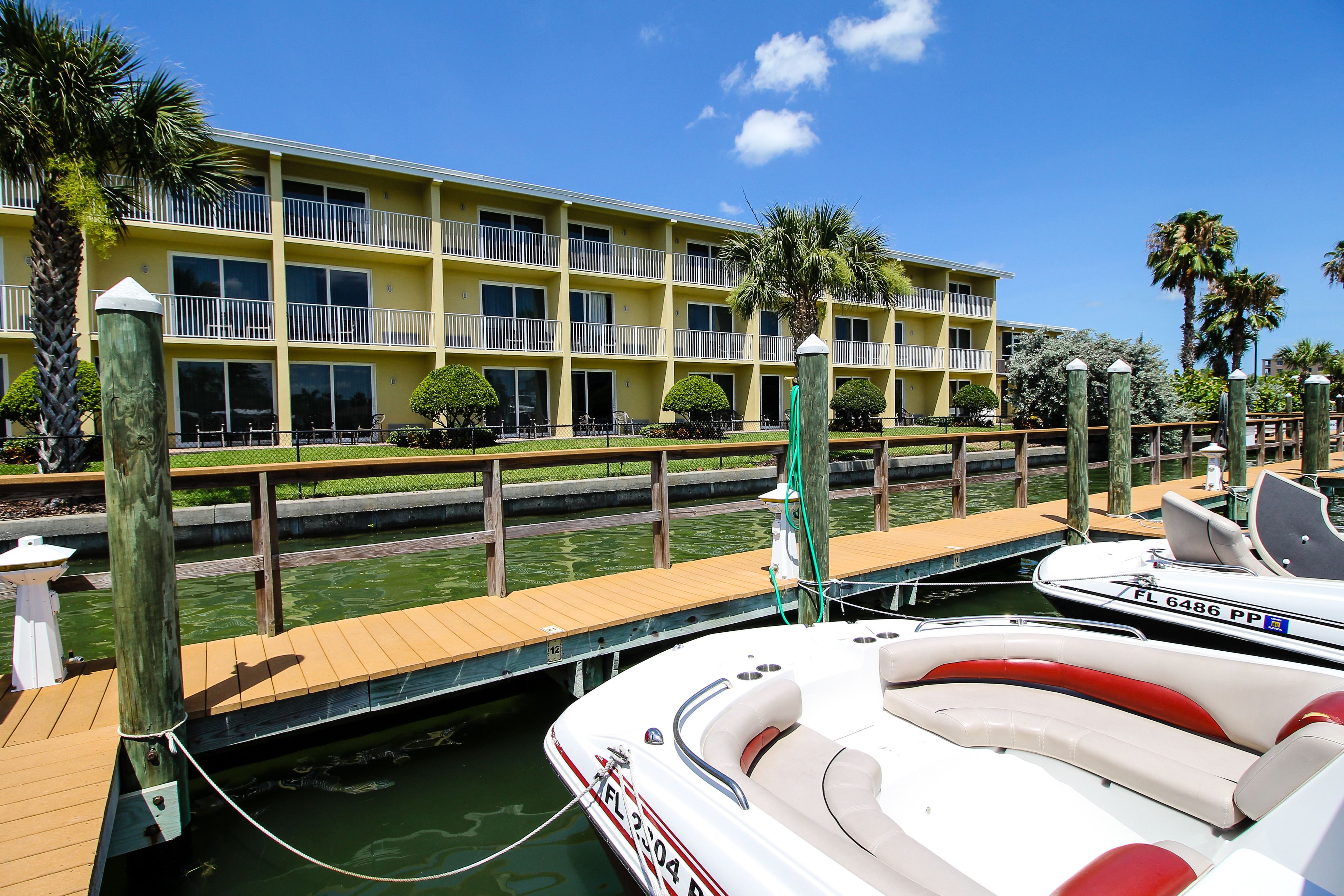 Un hotel frente al agua con un muelle, un bote y un edificio con balcones.