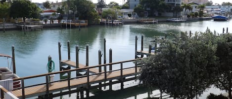Un molo sul lungomare con una passerella in legno, una recinzione in rete metallica e vista sull'acqua e sugli edifici sullo sfondo.