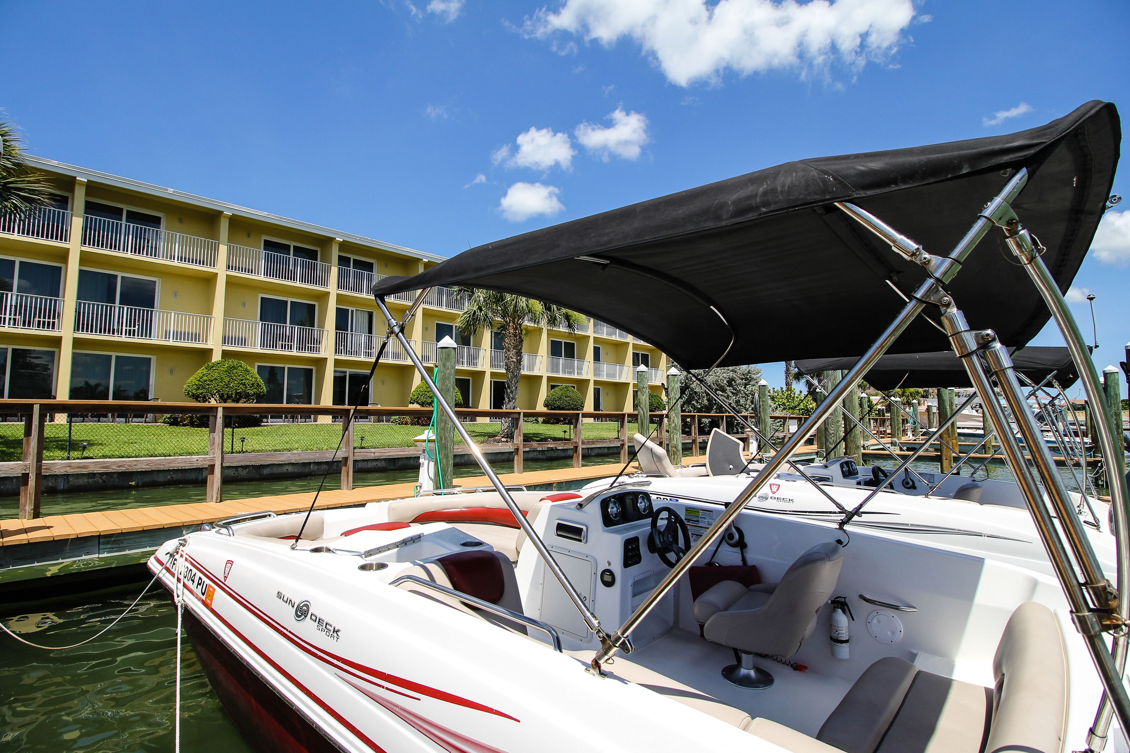 A boat docked at a marina with a yellow building in the background.