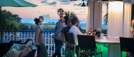 An outdoor seating area with wicker furniture and a bar with green lighting.