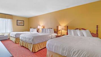 A hotel room with two beds, a desk, and a window with curtains.