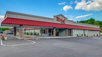 A Red Roof Inn & Suites with a red awning, a parking lot, and a clear sky.