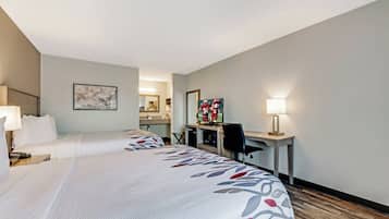 Une chambre d’hôtel avec deux lits, un bureau, une chaise, une télévision et une lampe.