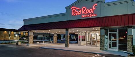 A Red Roof Inn & Suites with a clear sky, parking lot, and a modern building facade.