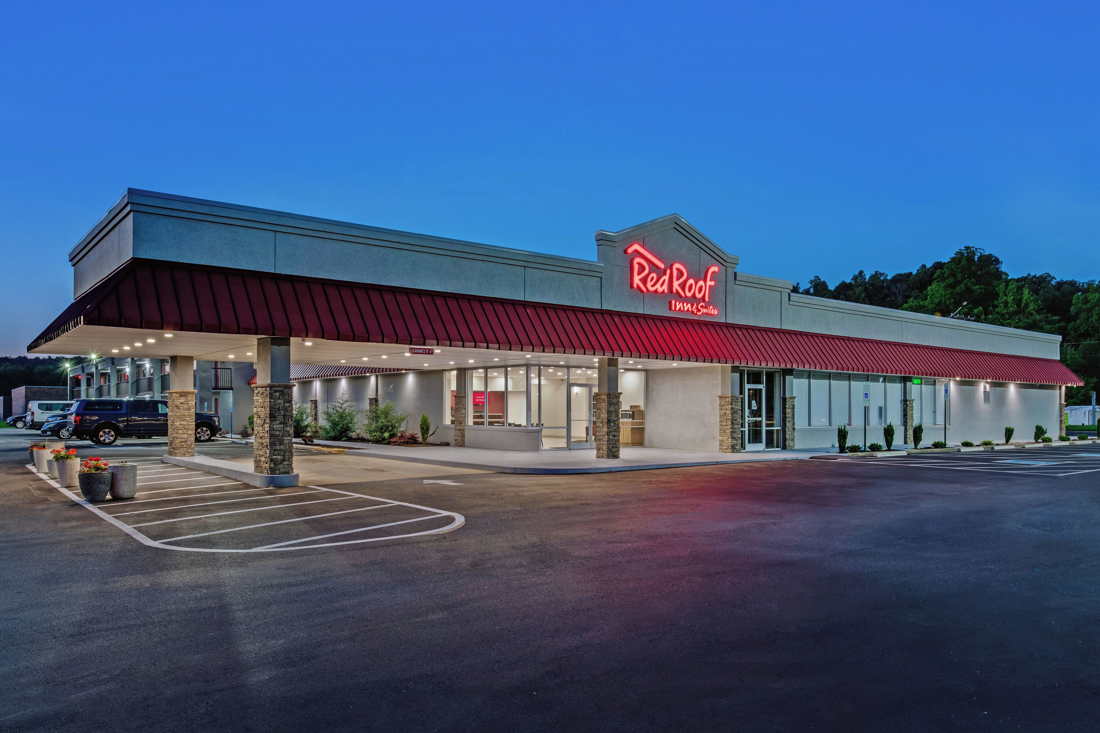 Un Red Roof Inn & Suites con estacionamiento techado y cielo despejado.