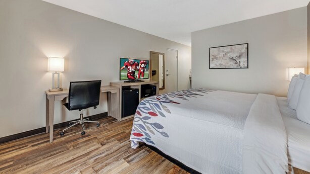 Ein Hotelzimmer mit Bett, Schreibtisch, Stuhl, Fernseher und Bildern an den Wänden.