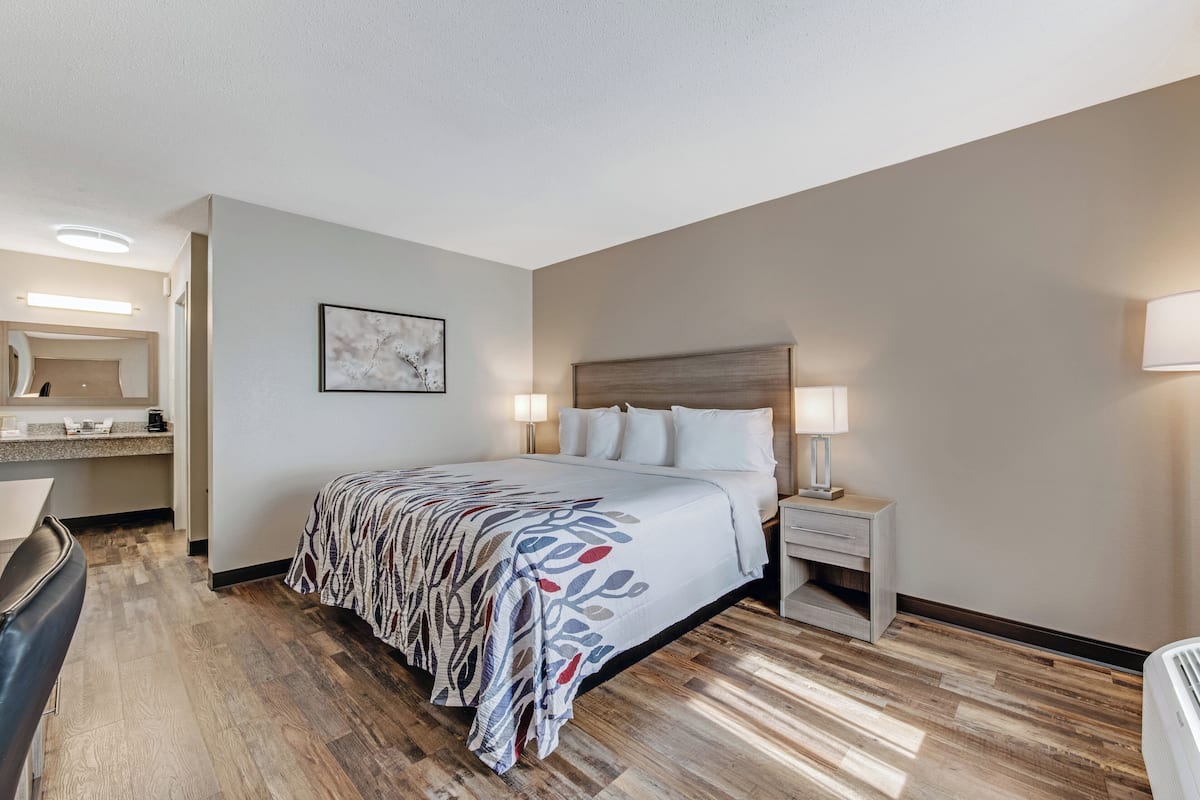 Une chambre d’hôtel comprenant un lit, des lampes de chevet, une table de chevet, un bureau et une chaise.