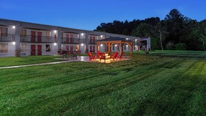 A multi-story hotel with outdoor seating and a fire pit area. - Red Roof Inn & Suites Wilkesboro (Wilkesboro)