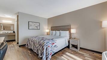 Habitación de hotel con cama, mesitas de noche, escritorio, silla, espejo y un cuadro en la pared.