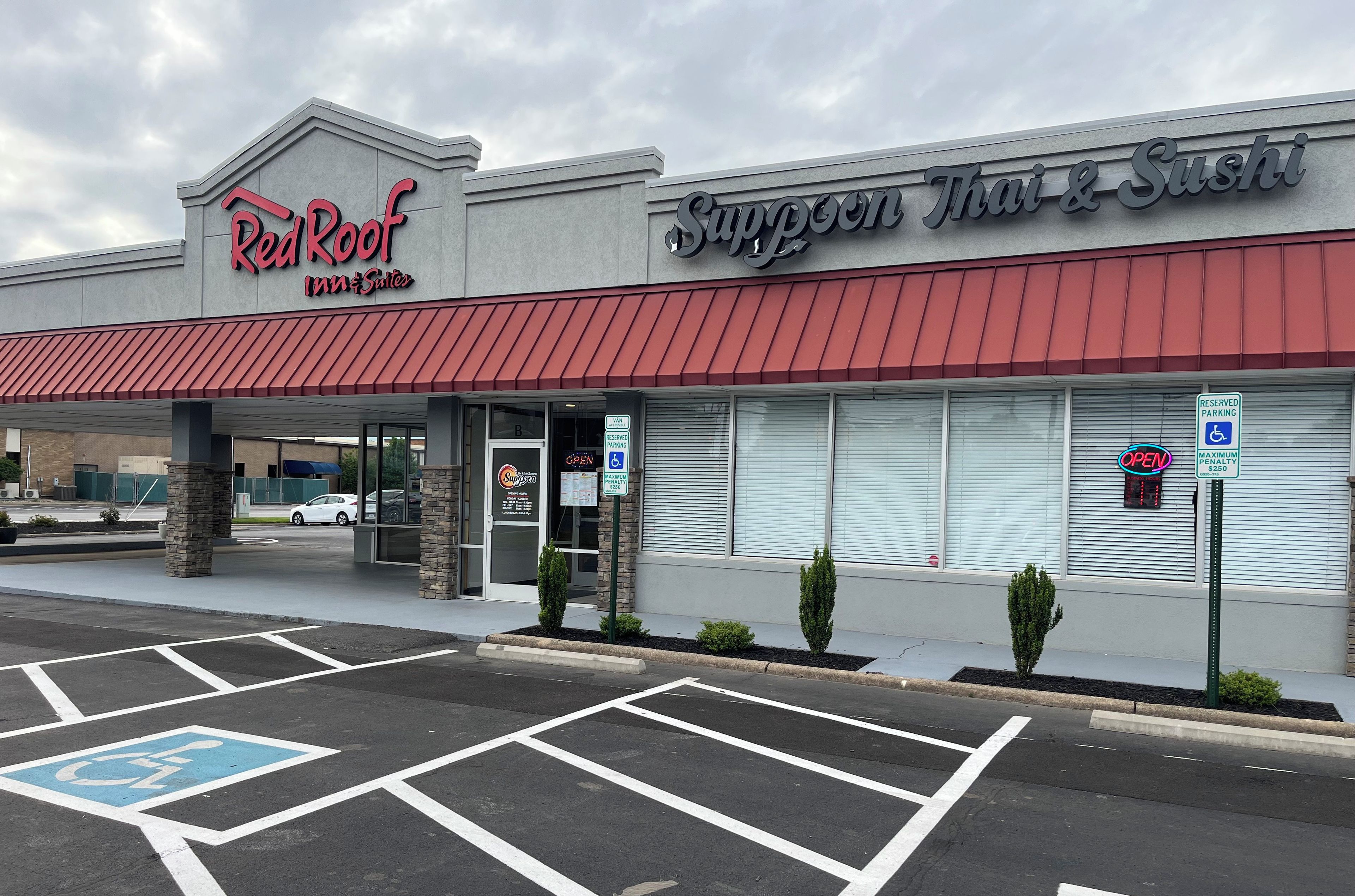 A Red Roof Inn & Suites and a Thai & Sushi restaurant with a parking lot and handicap parking signs.