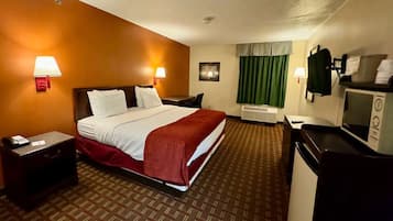 Une chambre d’hôtel équipée d’un lit, de tables de chevet, d’un bureau, d’un four à micro-ondes et d’une fenêtre avec des rideaux.