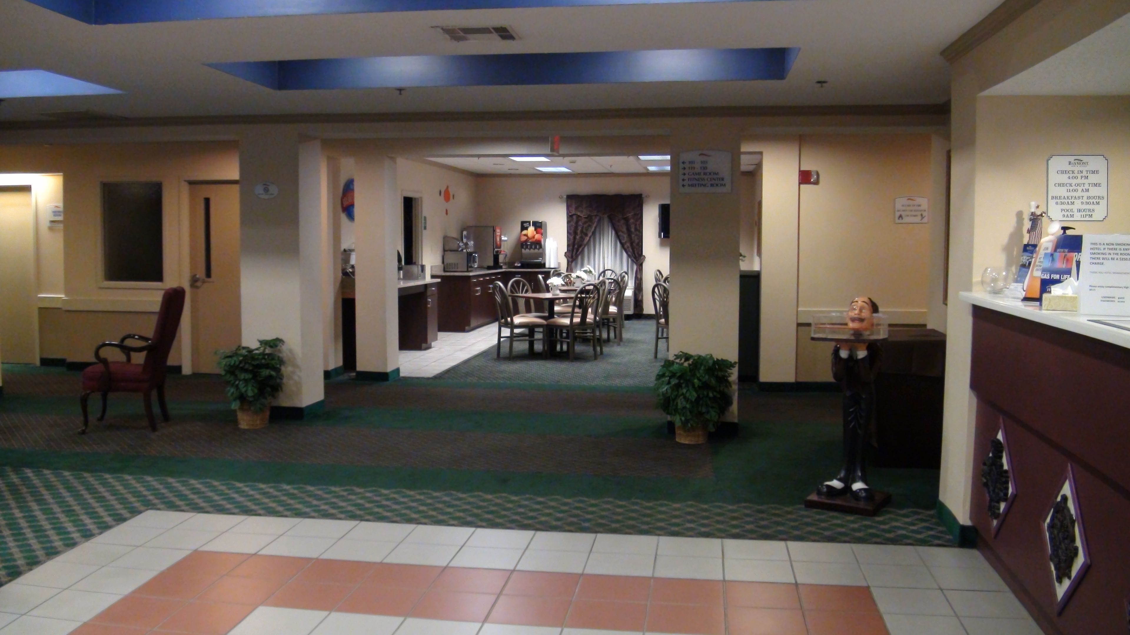 A hotel lobby with a reception desk, a dining area with a buffet, and a check-in counter.