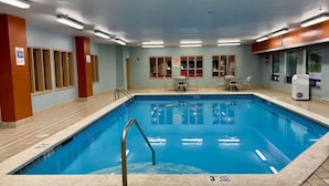 A swimming pool with a tiled deck, a lifeguard chair, and a pool table.