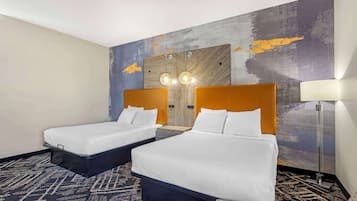 Habitación de hotel con dos camas, un espejo grande y una lámpara de pie.
