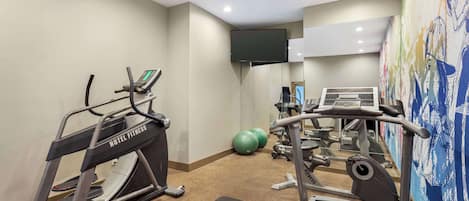 Un gimnasio de hotel con cintas de correr, bicicletas estáticas y pelotas de ejercicio.