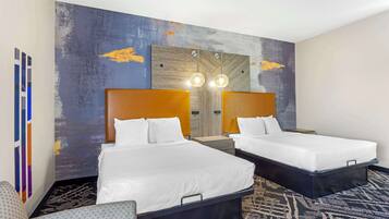 A hotel room with two beds, a large mirror, and a unique wall art piece.