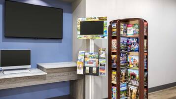 Un espace d’accueil équipé d’un écran plat, d’un ordinateur, d’un terminal en libre-service et d’un présentoir à magazines.