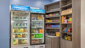 A vending machine with a variety of snacks and drinks, and adjacent shelves stocked with packaged goods. - Best Western Chambersburg (Chambersburg)