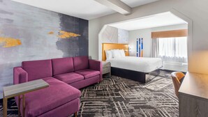 A hotel room with a large bed, a sofa, a small table, and a patterned rug. - Best Western Chambersburg (Chambersburg)