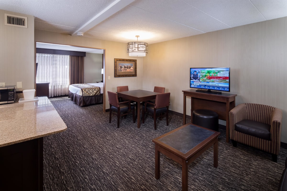 Una habitación de hotel con comedor, televisor, una mesita y una silla.