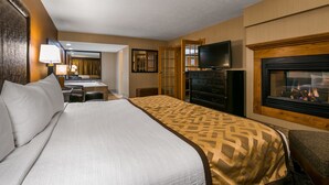 Una habitación de hotel con una cama grande, un escritorio con silla, un aparador, televisión y chimenea.