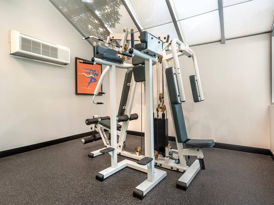 Ett gym med olika typer av träningsutrustning, ett inramat konstverk på väggen och ett fönster som släpper in naturligt ljus.