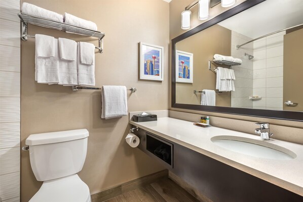 A modern bathroom with a toilet, sink, and large mirror. There are towels on a rack and a picture on the wall. - Best Western Plus Calgary Centre Inn (Calgary)