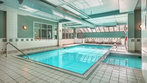 A large indoor swimming pool with clear blue water, tiled walls, and a ceiling with visible ductwork. - Best Western Plus Calgary Centre Inn (Calgary)